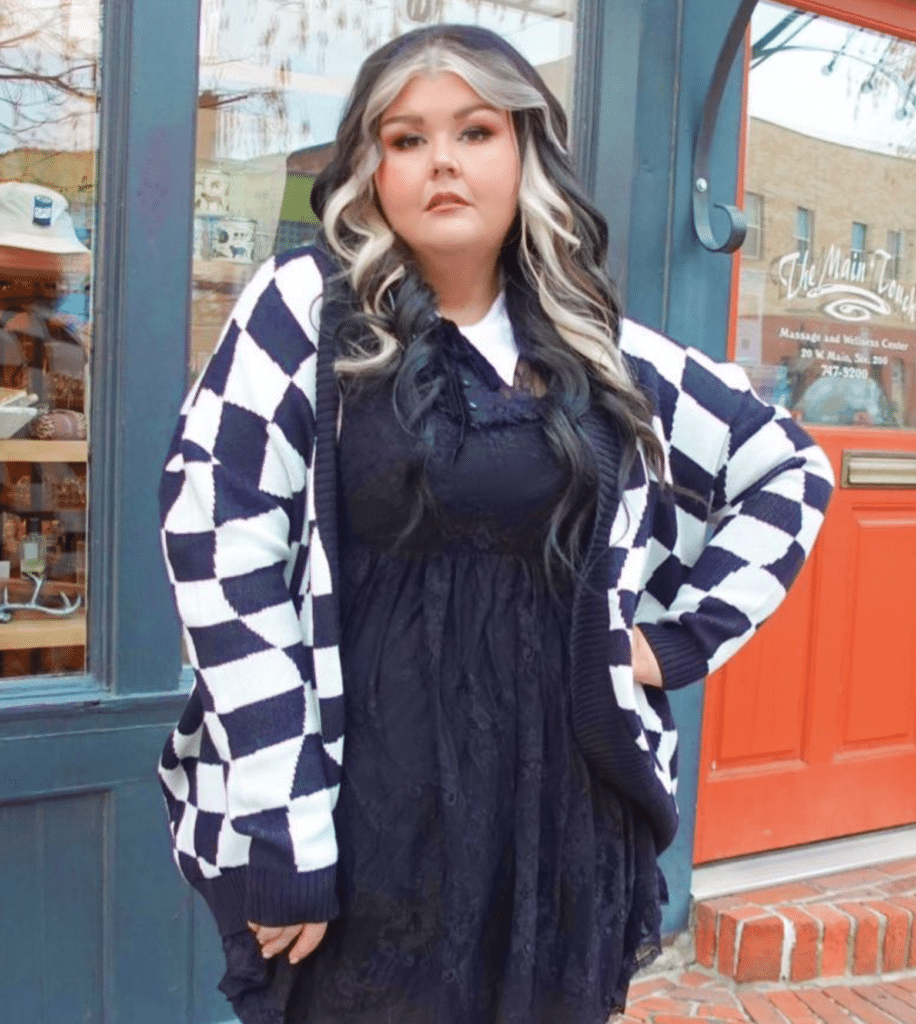 Photo by Alina Terry of Shannon Miller, wearing a black dress and black and white cardigan in front of Boots Bakery in Spokane, WA